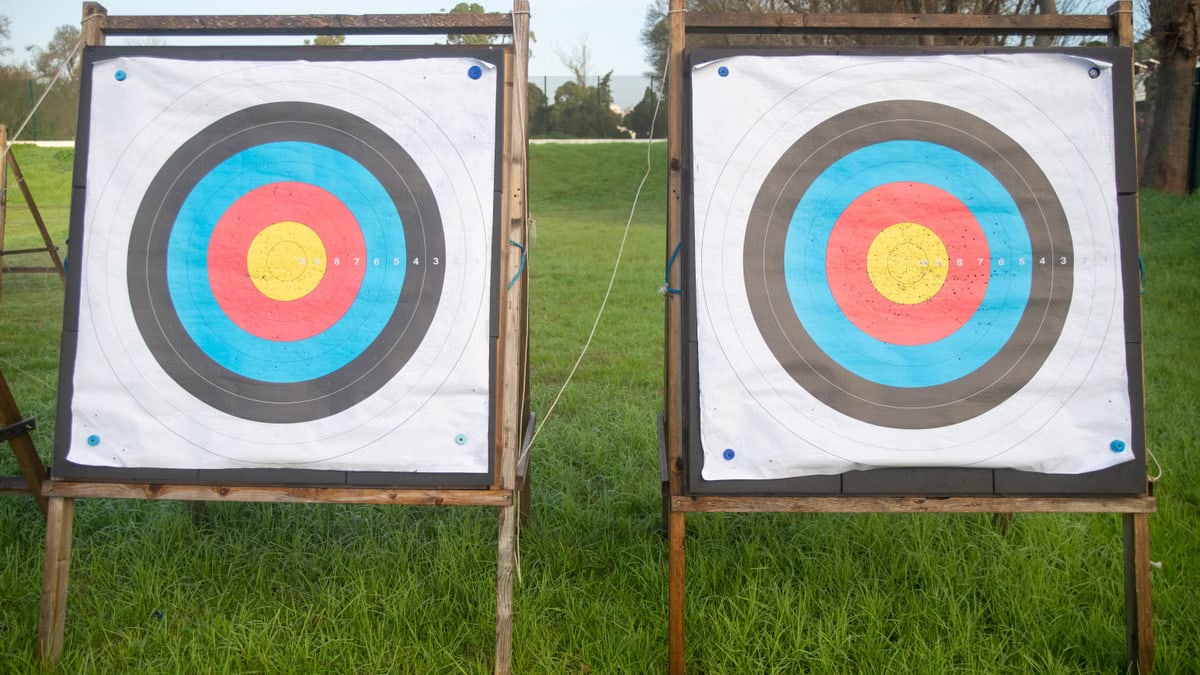 Two colorful archery targets standing on a green field under clear skies, perfect for outdoor sports enthusiasts.
